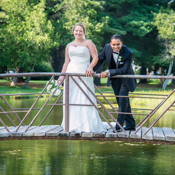 photography bride and groom on bridge over lake surrounded by trees