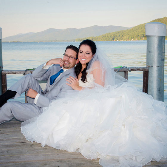 photography bride and groom posing on dock by lake in mountains